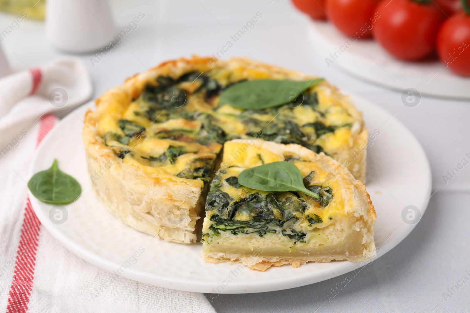 Photo of Delicious pie with spinach on white tiled table, closeup