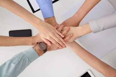 Young people holding hands together over table, top view. Team victory concept