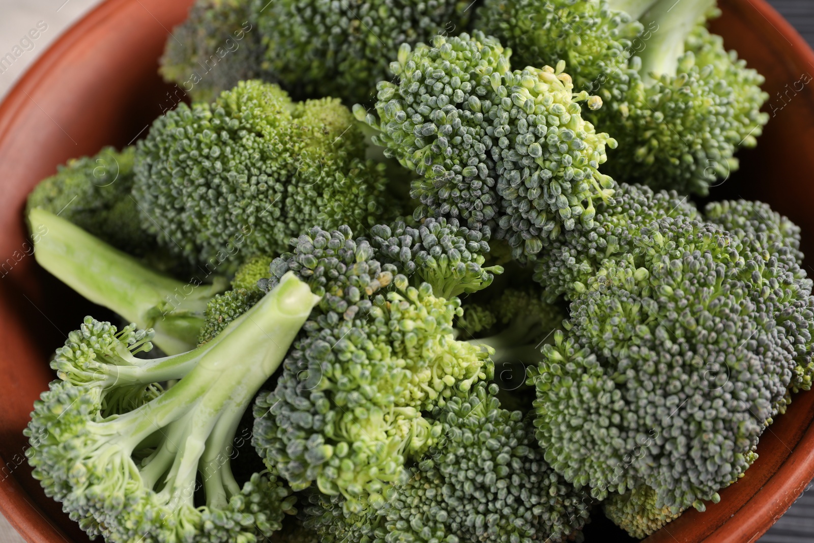 Photo of Bowl with fresh raw broccoli on table, closeup