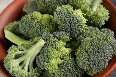 Photo of Bowl with fresh raw broccoli on table, closeup