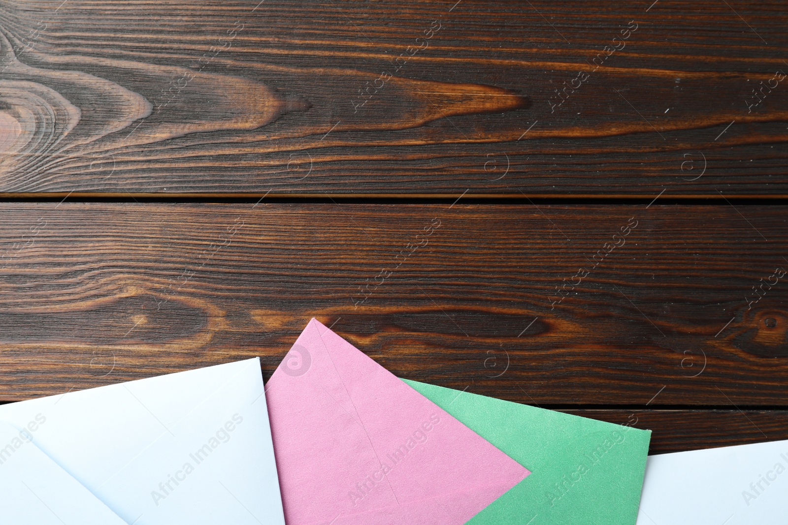 Photo of Colorful paper envelopes on wooden background, flat lay. Space for text