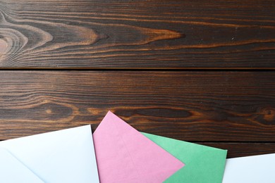 Colorful paper envelopes on wooden background, flat lay. Space for text