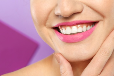 Photo of Young woman wearing beautiful lipstick on color background, closeup