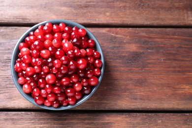 Photo of Fresh ripe cranberries in bowl on wooden table, top view. Space for text