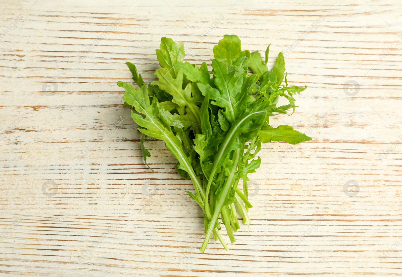 Photo of Fresh arugula on white wooden table, flat lay