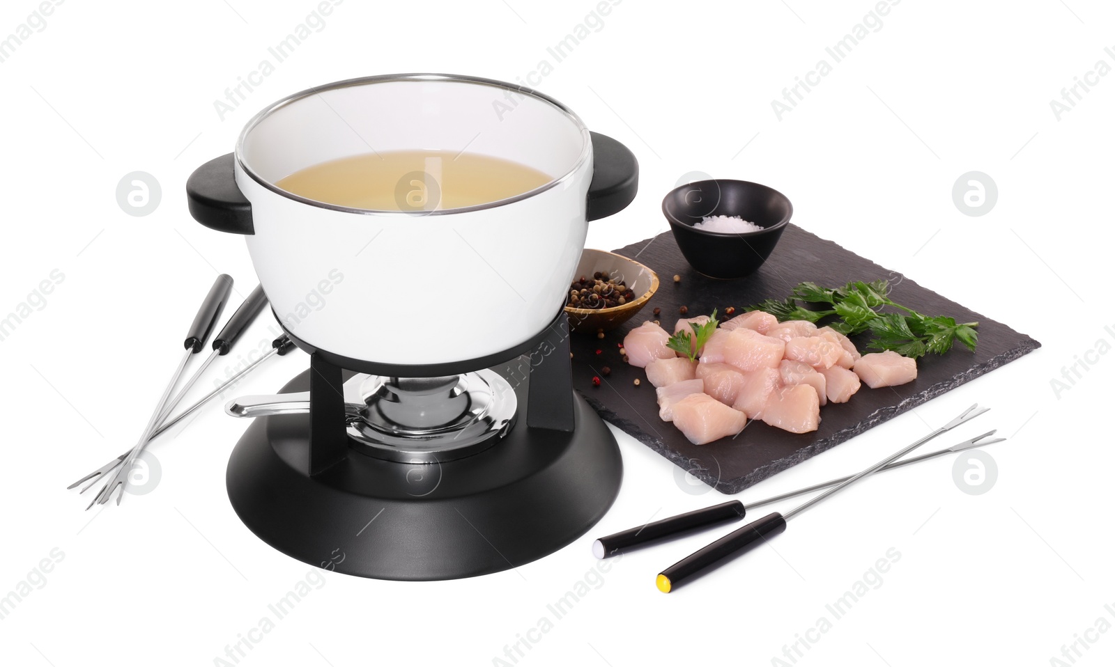 Photo of Oil in fondue pot, forks, pieces of raw meat, salt and pepper isolated on white