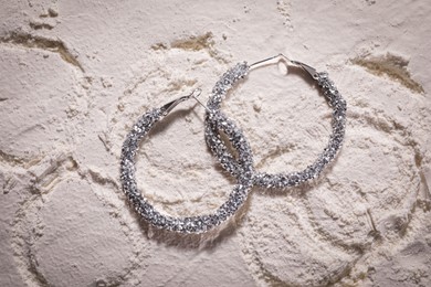 Photo of Elegant jewelry. Luxury earrings on powder, flat lay