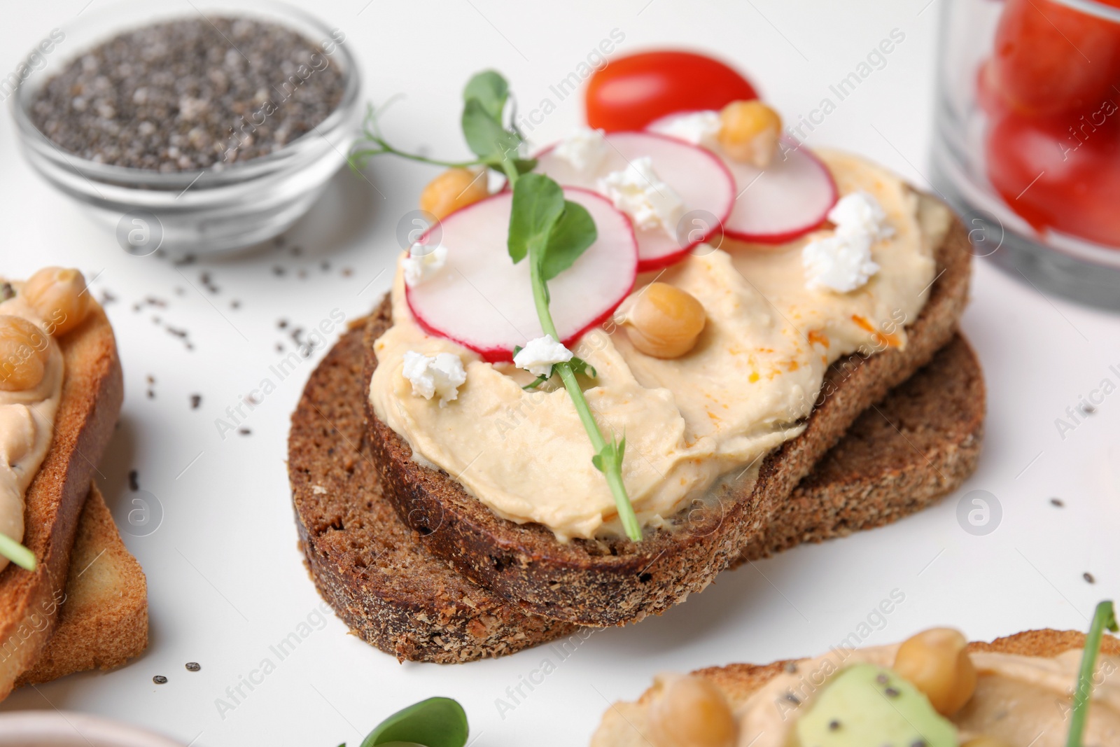 Photo of Delicious sandwich with hummus and ingredients on white table