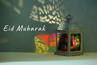 Image of Eid Mubarak greeting card. Arabic lantern on light surface at night