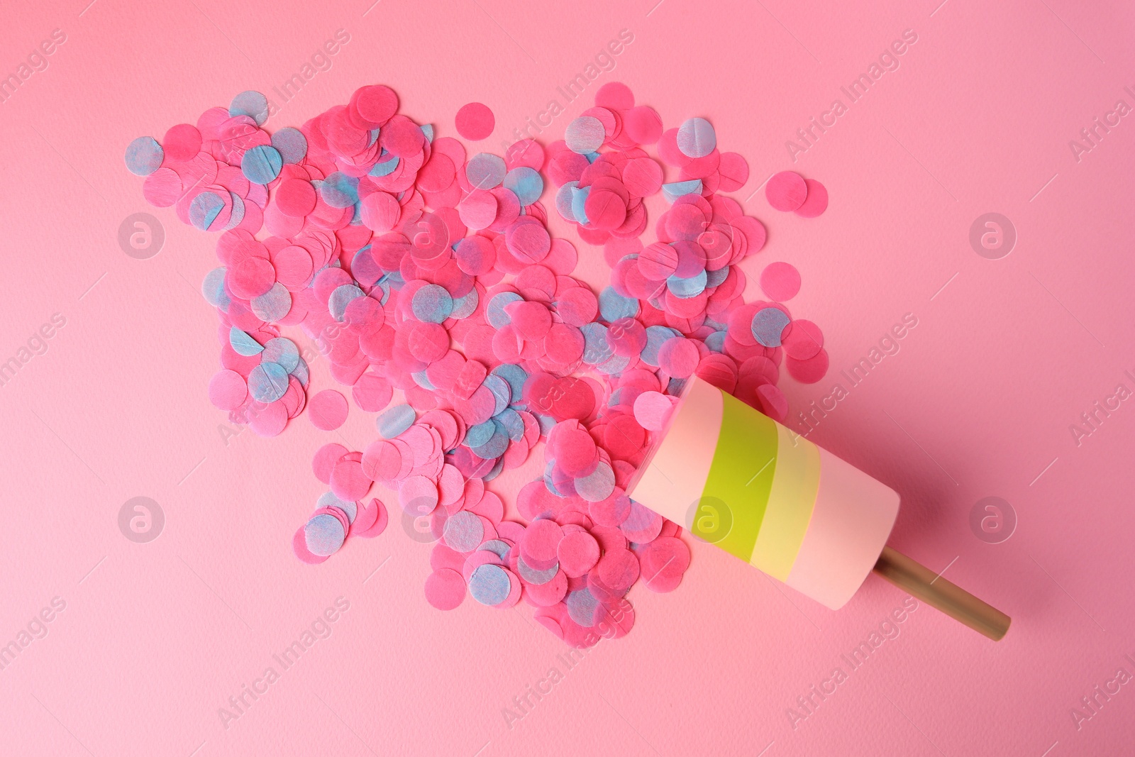 Photo of Colorful confetti bursting out of party popper on pink background, flat lay