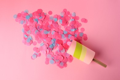 Colorful confetti bursting out of party popper on pink background, flat lay