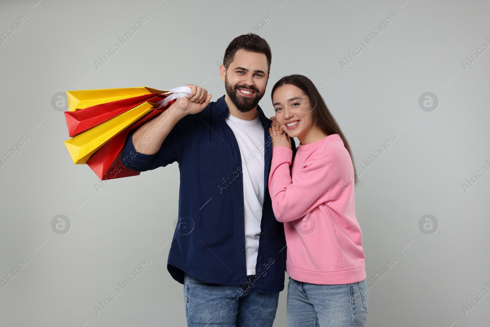 Photo of Happy couple with shopping bags on grey background