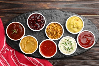 Different tasty sauces in bowls on wooden table, top view