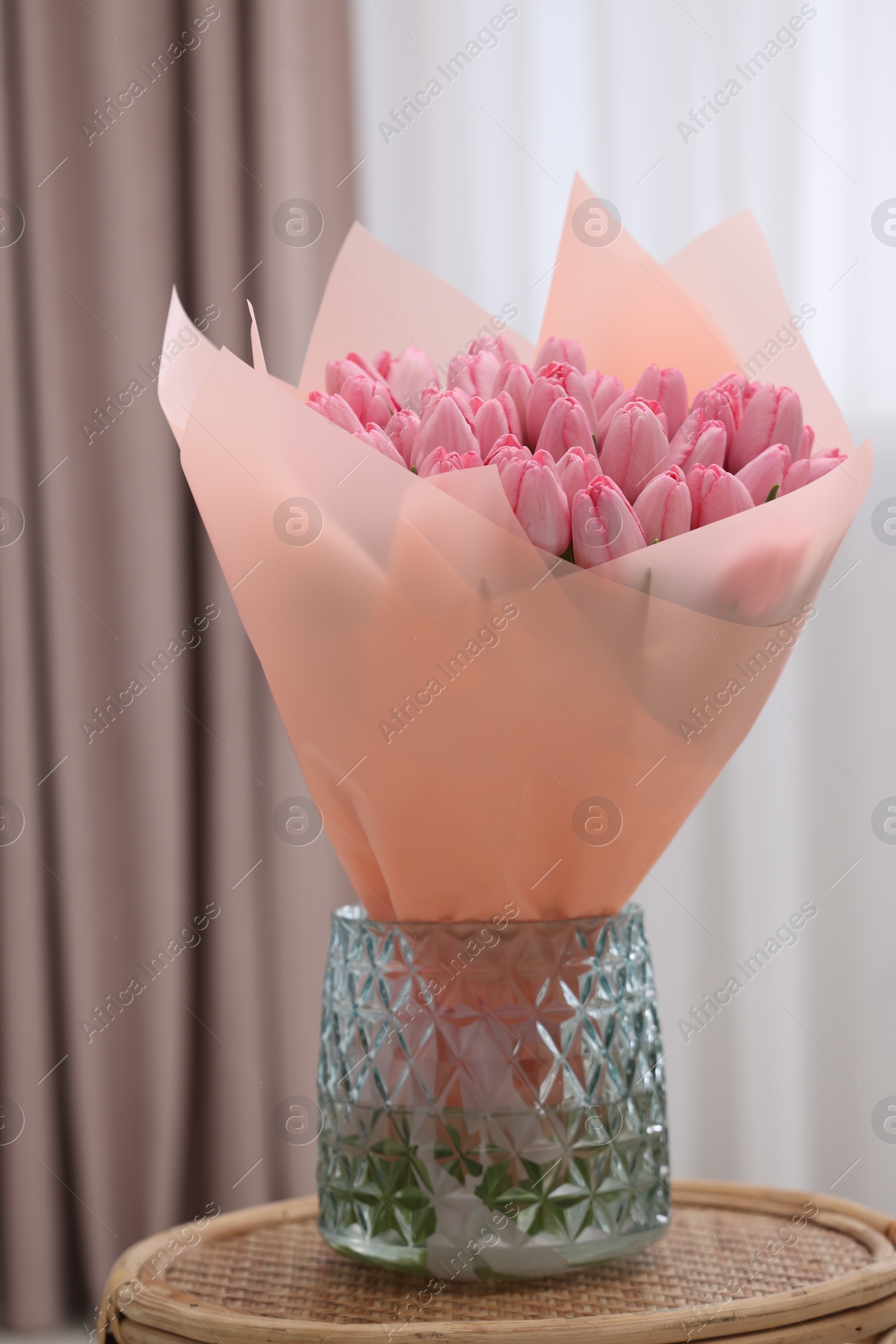 Photo of Bouquet of beautiful pink tulips in vase on table indoors