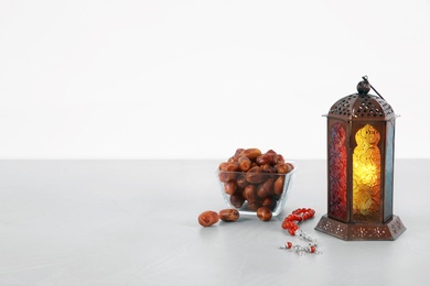 Muslim lamp, dates and prayer beads on table against white background. Space for text