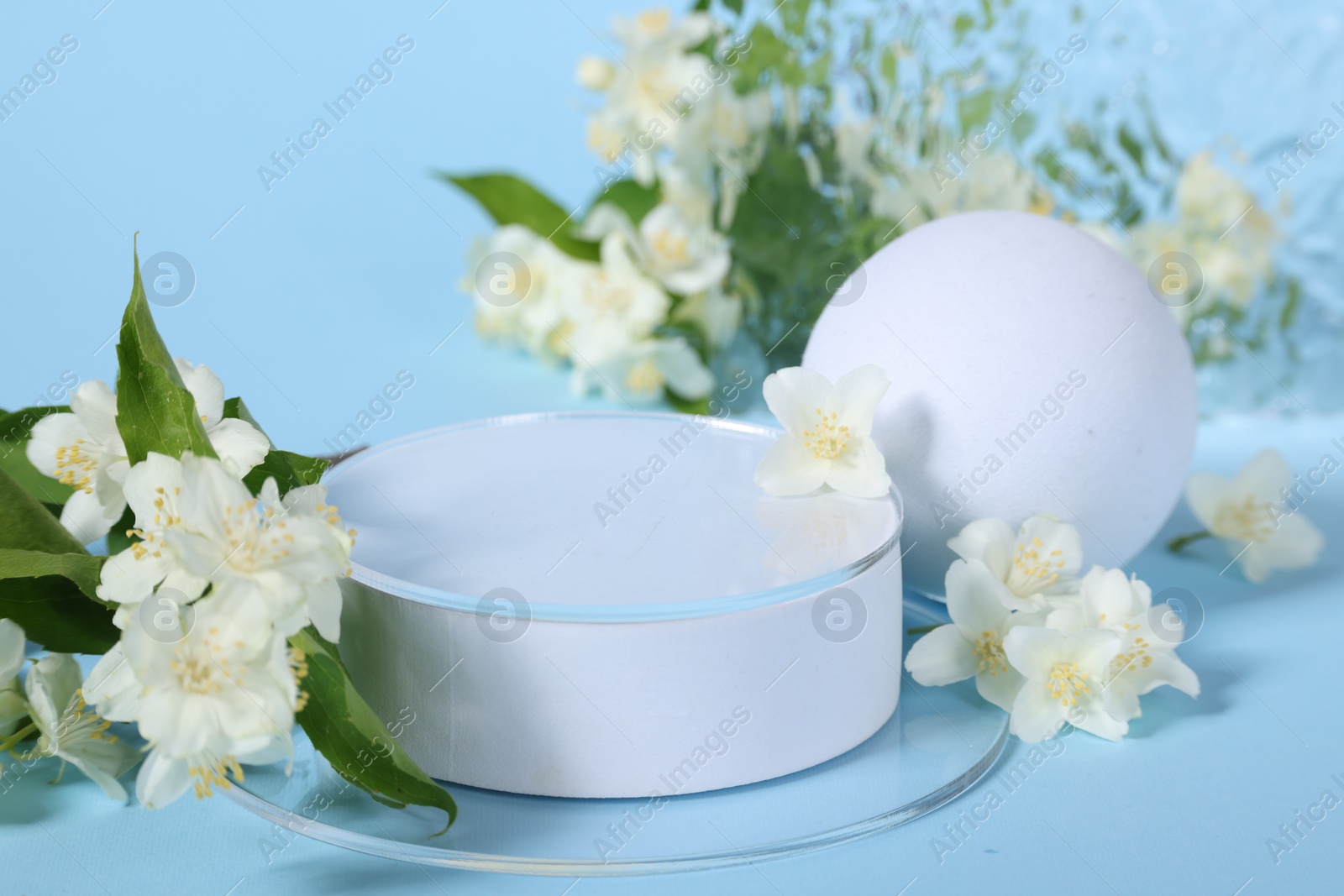 Photo of Presentation of product. White podium and beautiful jasmine flowers on light blue background, closeup