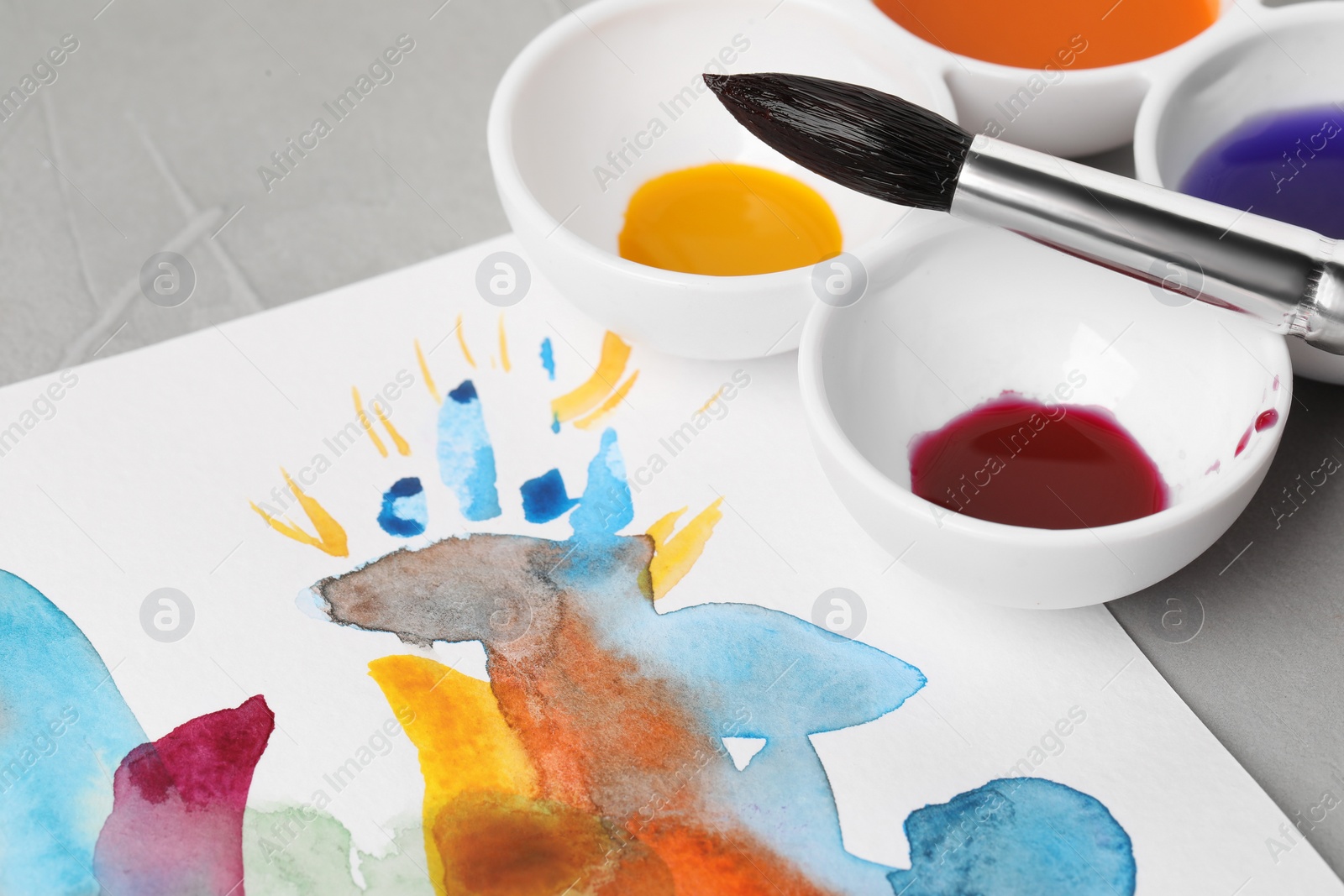 Photo of Abstract watercolor painting, colorful paints and brush on grey table, closeup