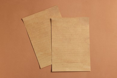 Photo of Sheets of old parchment paper on brown background, flat lay