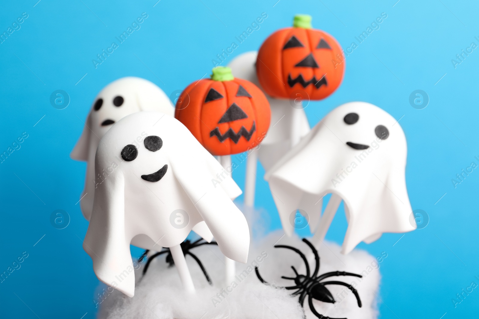 Photo of Delicious Halloween themed cake pops on light blue background, closeup