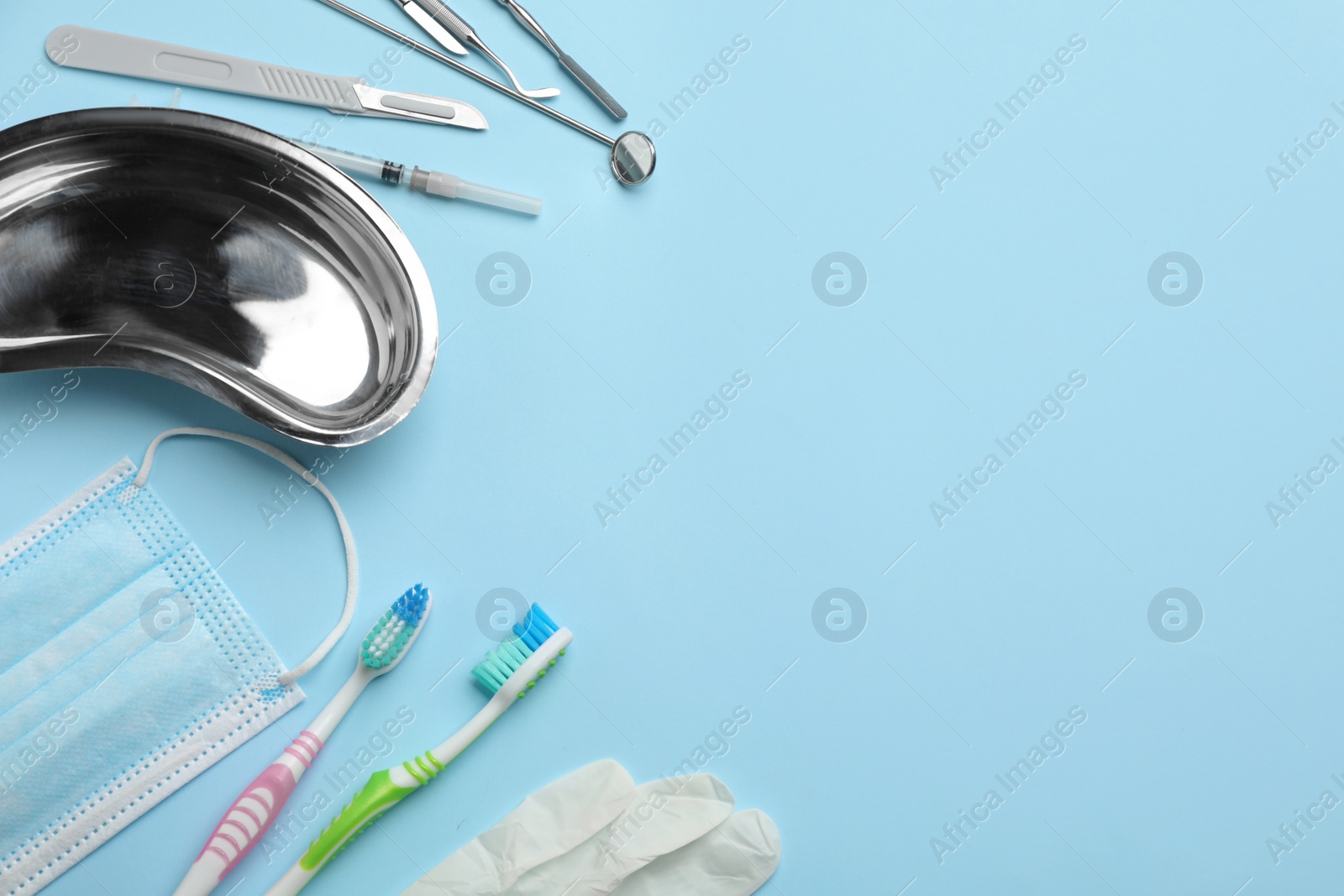 Photo of Set of different dentist's tools, face mask, toothbrushes and glove on light blue background, flat lay. Space for text