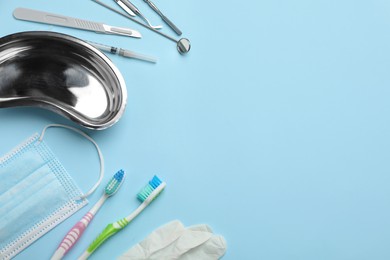 Set of different dentist's tools, face mask, toothbrushes and glove on light blue background, flat lay. Space for text