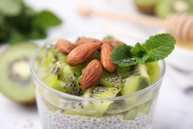 Delicious dessert with kiwi, chia seeds and almonds in glass, closeup