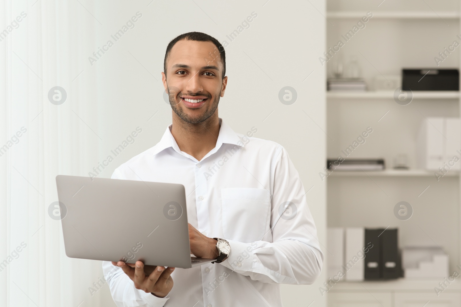 Photo of Handsome young man with laptop at home