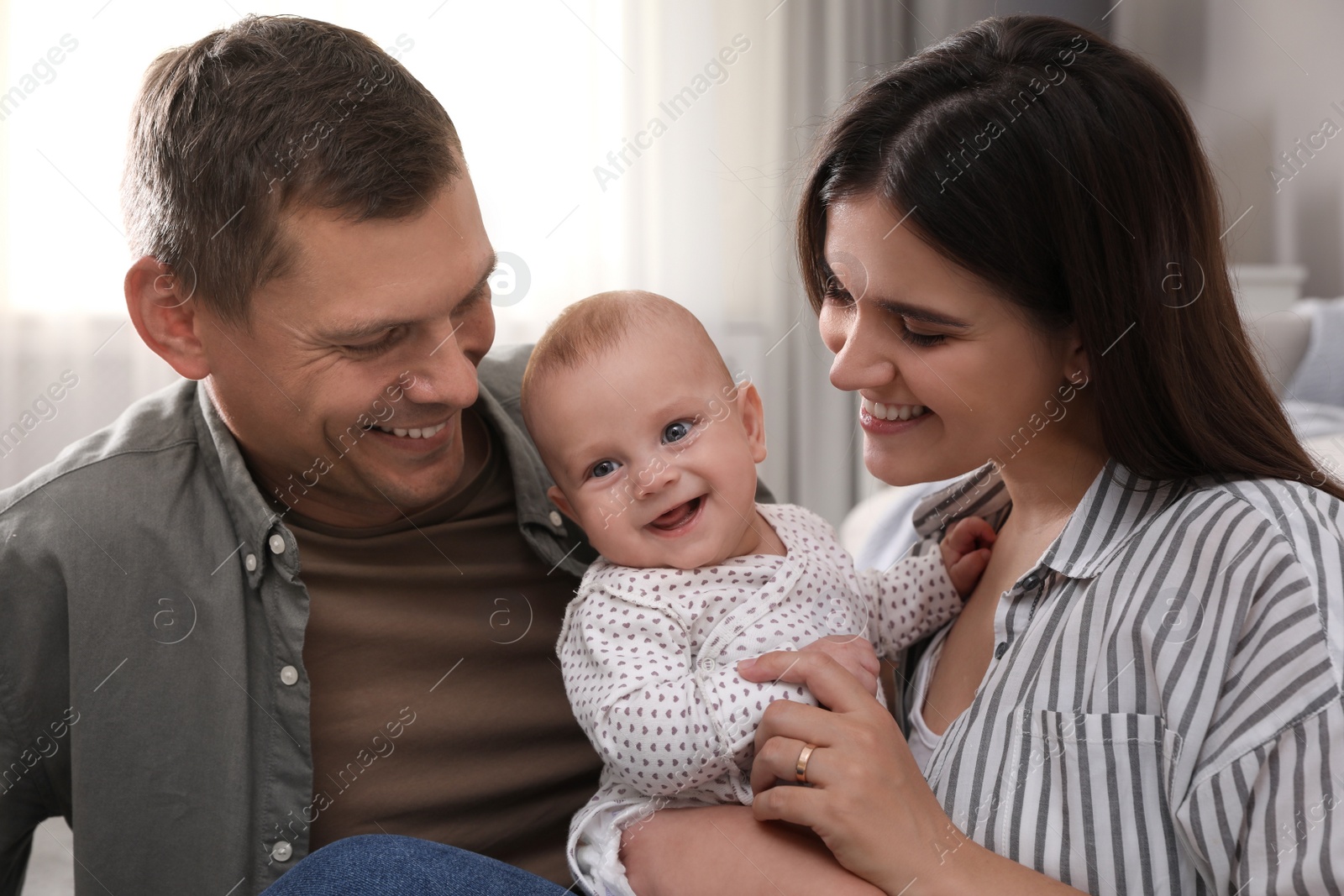 Photo of Happy family with their cute baby at home