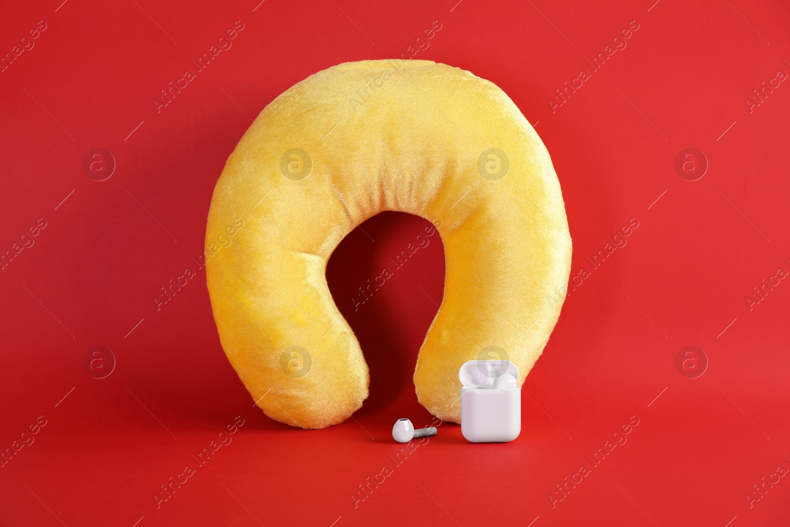 Photo of Yellow travel pillow and earphones on red background