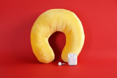 Photo of Yellow travel pillow and earphones on red background