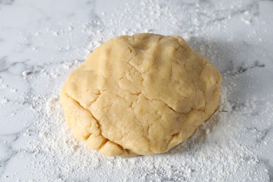 Photo of Making shortcrust pastry. Raw dough and flour on white marble table