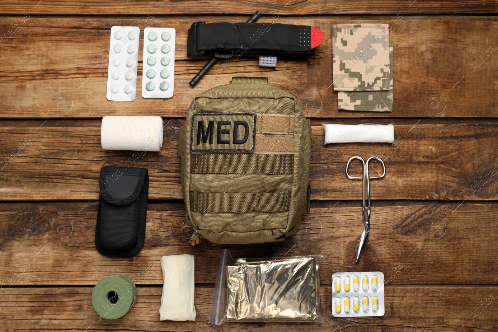 Photo of Military first aid kit on wooden table, flat lay