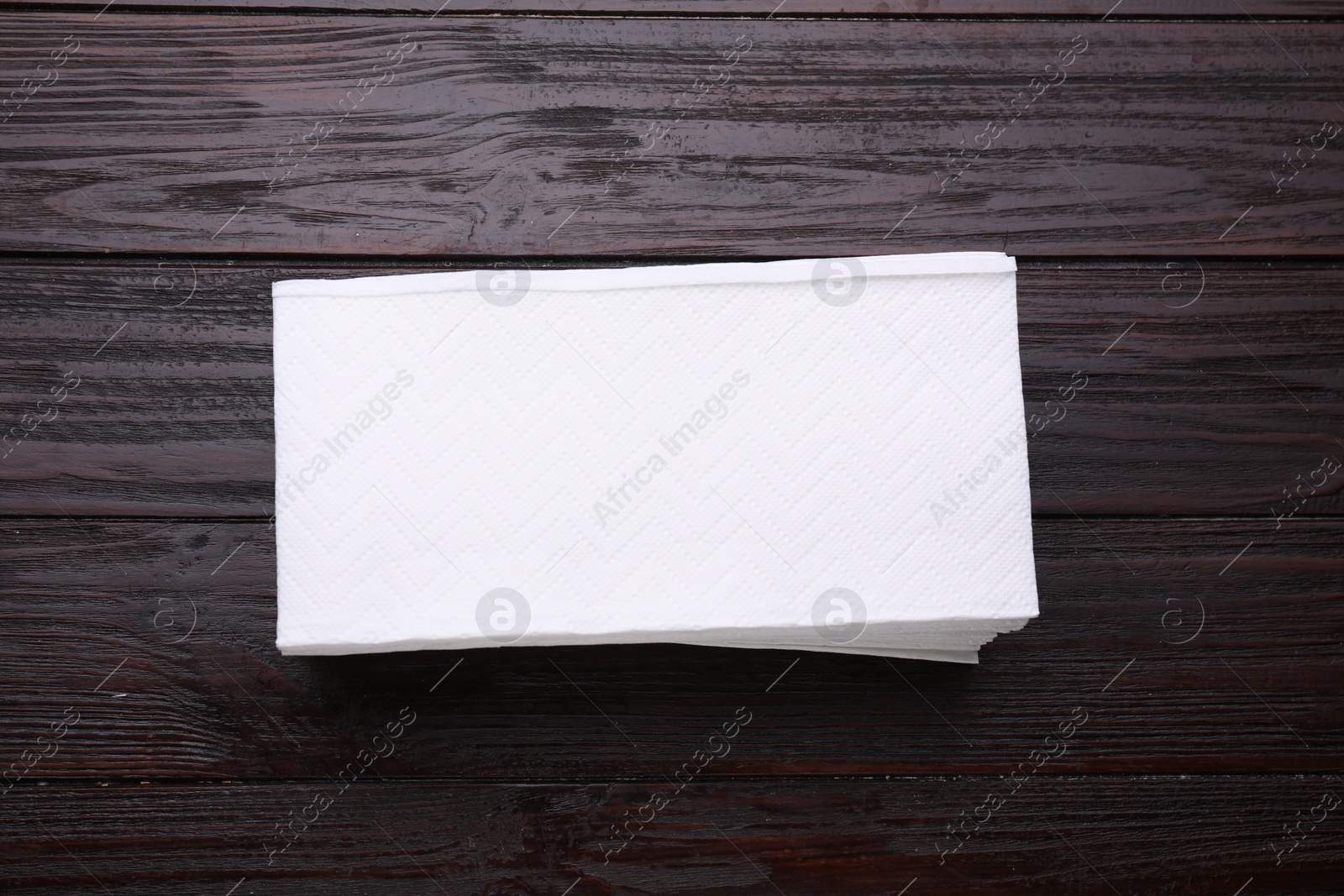 Photo of Stack of clean tissue towels on wooden table, top view