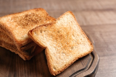 Photo of Board with toasted bread on wooden background, closeup