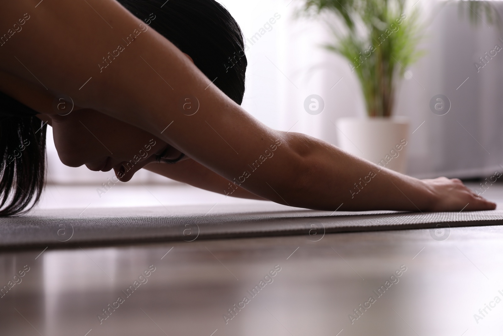 Photo of Young woman practicing extended child's asana in yoga studio, closeup. Utthita Balasana pose