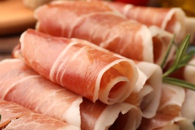Photo of Rolled slices of delicious jamon with rosemary, closeup
