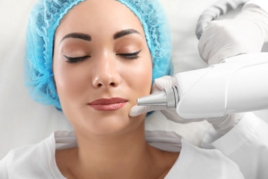 Photo of Woman undergoing laser tattoo removal procedure in salon, closeup