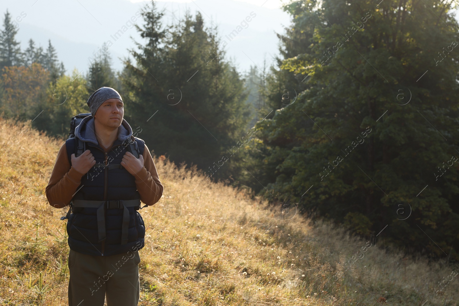 Photo of Tourist with backpack in nature on sunny day. Space for text