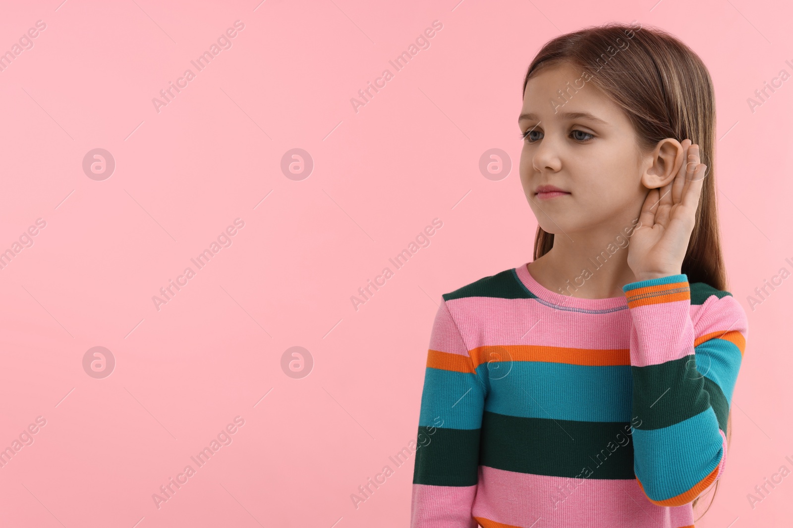 Photo of Little girl with hearing problem on pink background, space for text