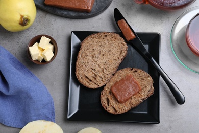 Photo of Bread with delicious quince paste on grey table, flat lay