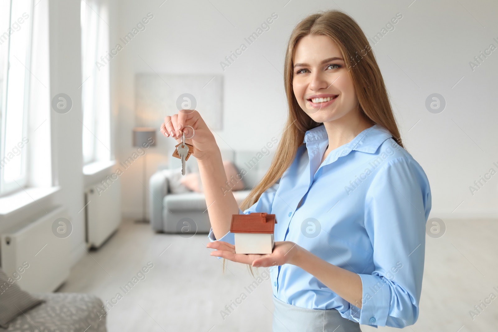 Photo of Beautiful real estate agent with house model and key indoors