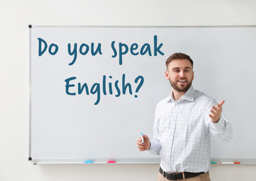 Image of Young English teacher near whiteboard in classroom