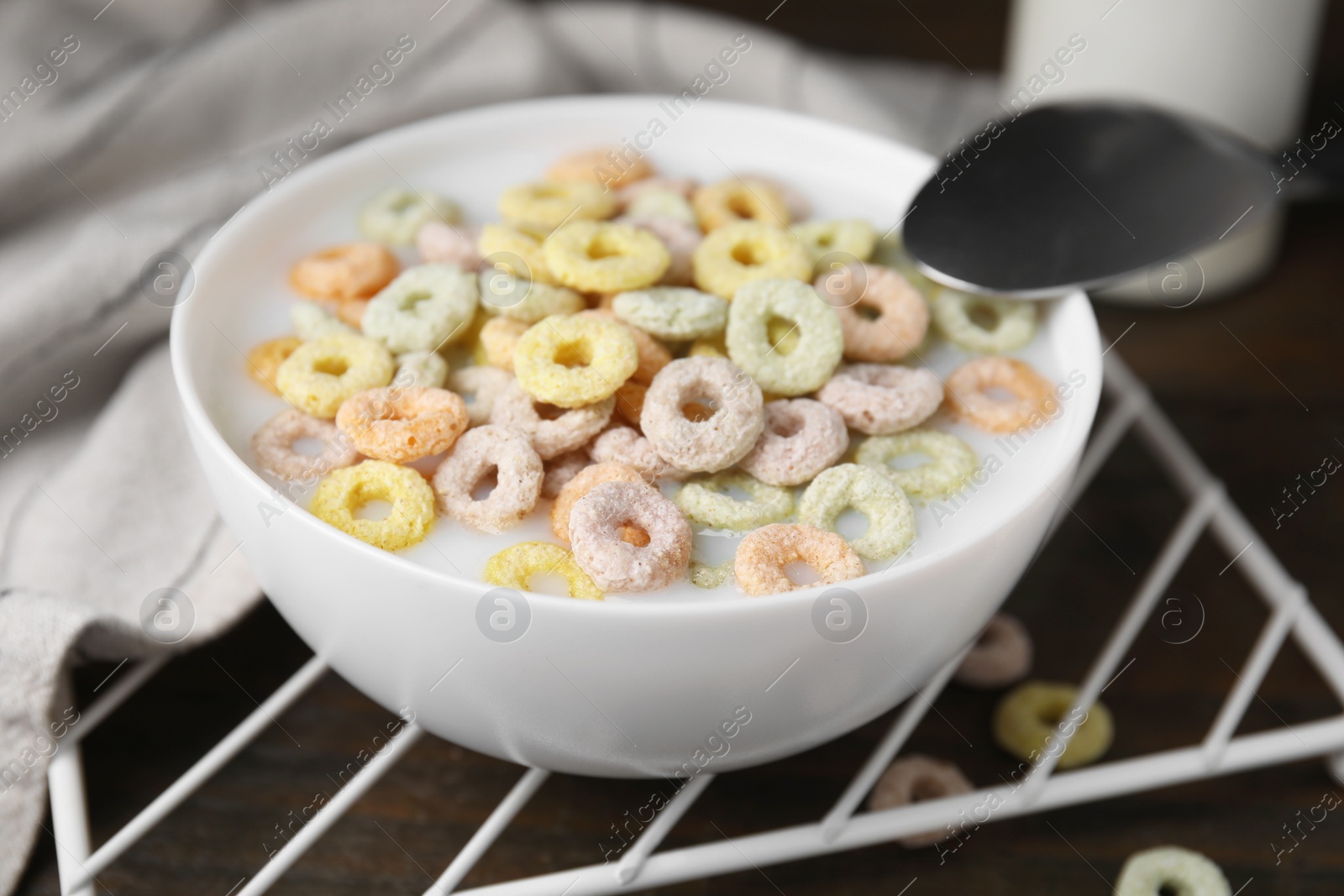 Photo of Cereal rings and milk in bowl on table, closeup