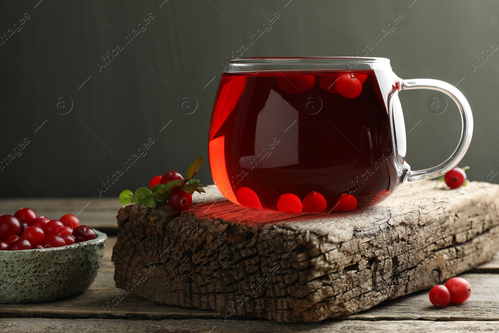 Photo of Delicious cranberry tea and berries on wooden table, closeup