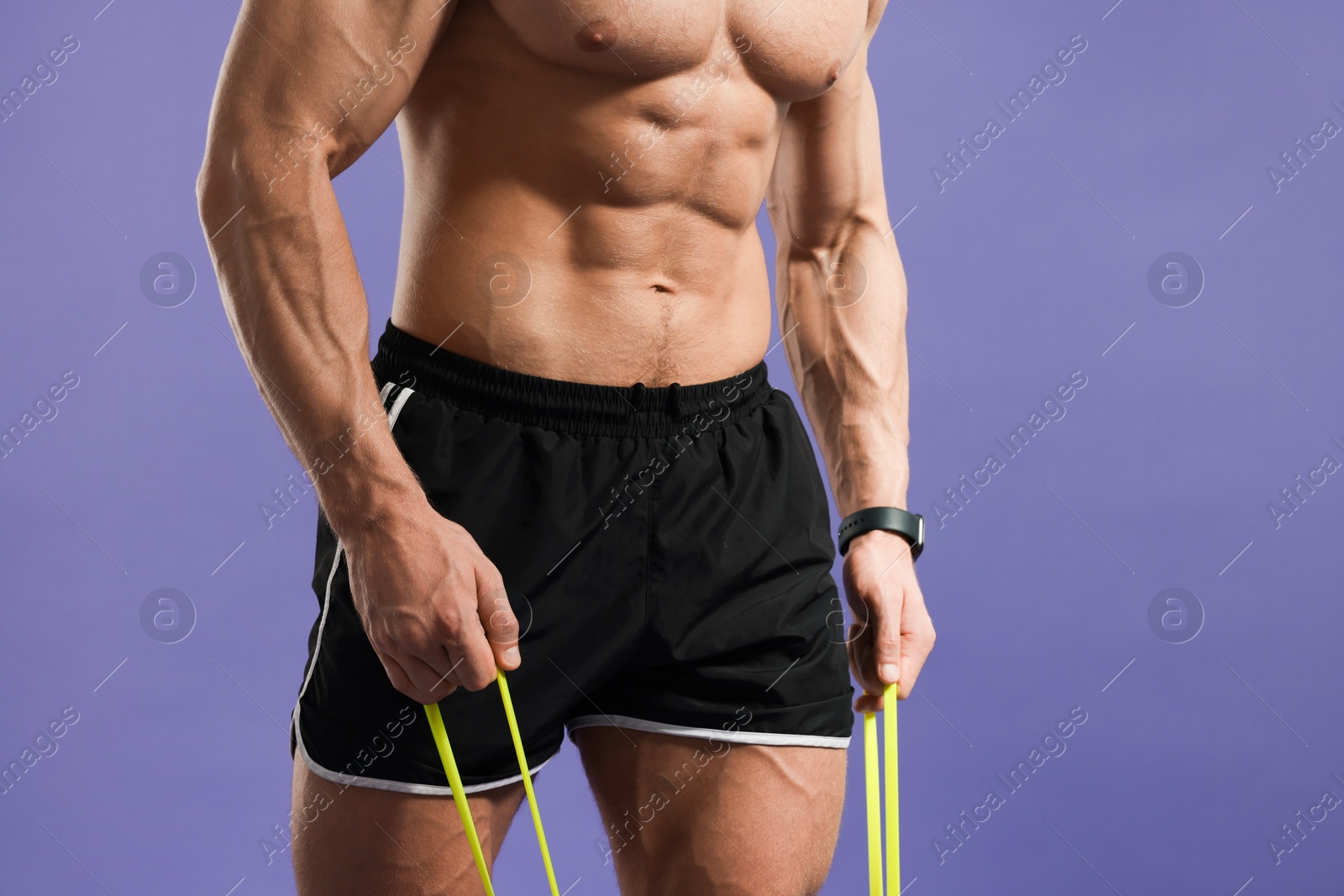 Photo of Muscular man exercising with elastic resistance band on purple background, closeup