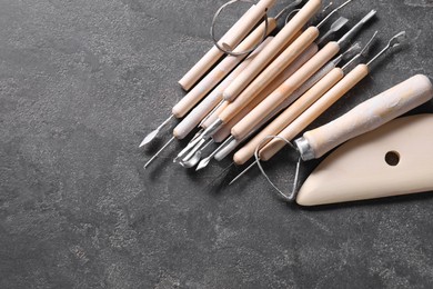 Photo of Set of different clay crafting tools on grey table, top view. Space for text