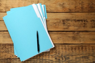 Photo of Turquoise files with documents and pen on wooden table, top view. Space for text