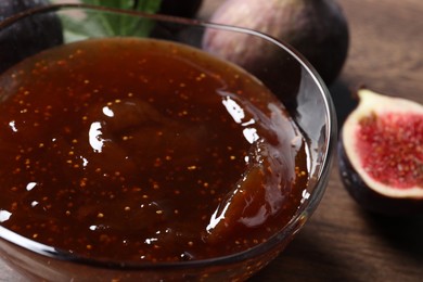 Photo of Glass bowl with tasty fig jam and fresh fruits on table, closeup