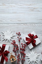 Photo of Flat lay composition with beautiful gift boxes and different Christmas decor on white wooden table. Space for text