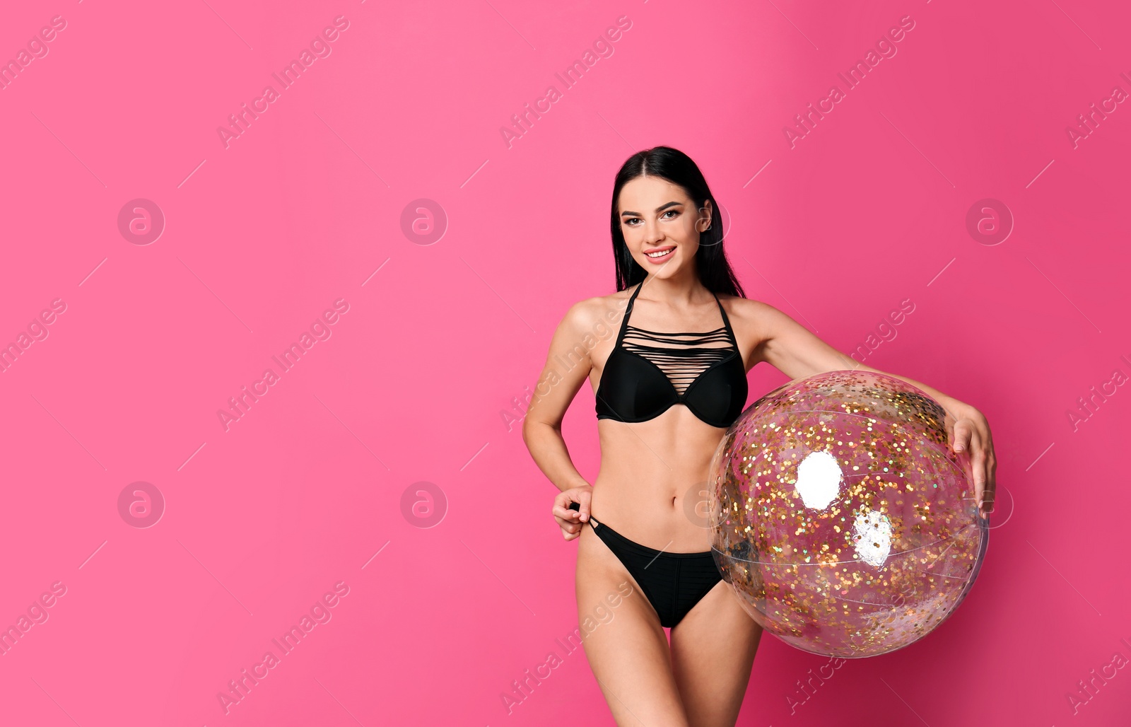 Photo of Beautiful young woman in stylish bikini with beach ball on pink background. Space for text